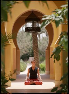 Woman practises yoga under an arch