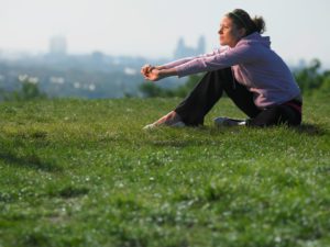 Woman sitting on grassy area overlooking a city